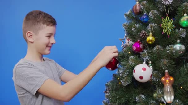크리스마스 트리를 구슬로 장식하는 행복 한 소년. — 비디오
