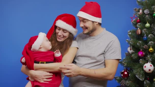 クリスマスツリーの近くにいる若い幸せな家族笑顔の波こんにちは家族の休日や新年のセルフィーやビデオメッセージの概念を作る. — ストック動画