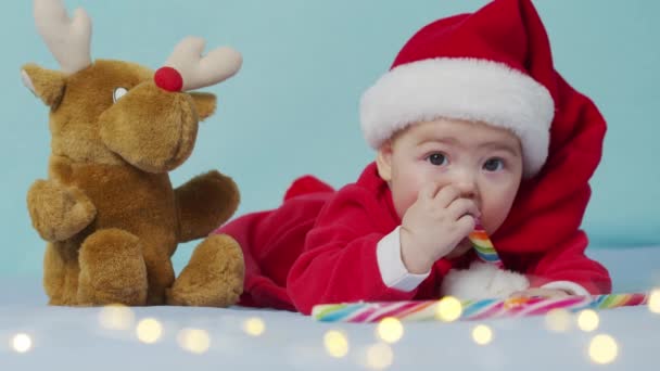 รูปภาพคริสต์มาสของเด็กสาวทารกแรกเกิดที่น่ารัก ใส่หมวกและชุดซานต้า ฤดูหนาว . — วีดีโอสต็อก