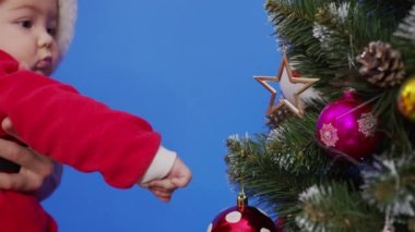 Anne bebeğiyle Noel ağacının yanında. Anne ve bebek yeni yıl ağacı ile oynuyorlar..