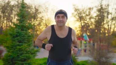 Kamu parkında yolda koşan kıdemli bir adam. Sağlık yaşam tarzı ve egzersiz kavramı.