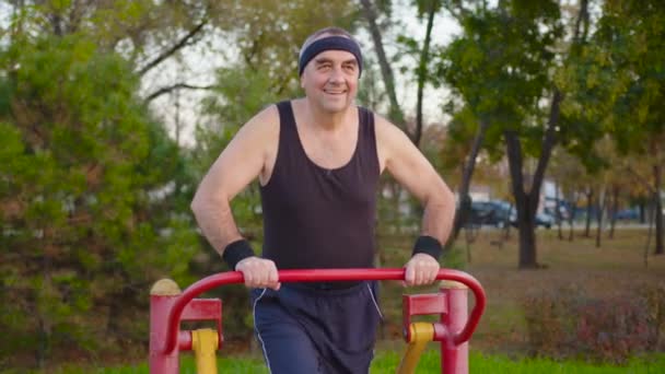 Oudere man oefenen in en outdoor gym. — Stockvideo
