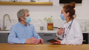 Beyaz önlüklü çok ırklı kadın doktor portresi ve sağlık raporundaki iyi haberler ve hastanede gülümseyen kıdemli hasta hakkında tatmin edici konuşmalar. Karışık ırk hemşiresi ve yaşlı beyaz adam.