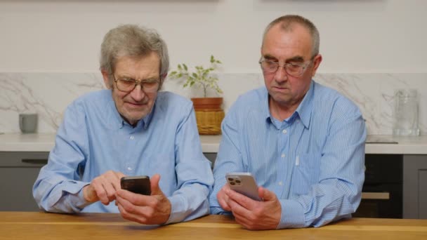 Souriant aîné des années 80 adultes grands-pères apprennent application de téléphone mobile, heureux homme âgé des années 70 tenir des messages texte smartphone dans les médias sociaux lire des nouvelles, personne âgée en utilisant le concept gadget technologique à la maison — Video