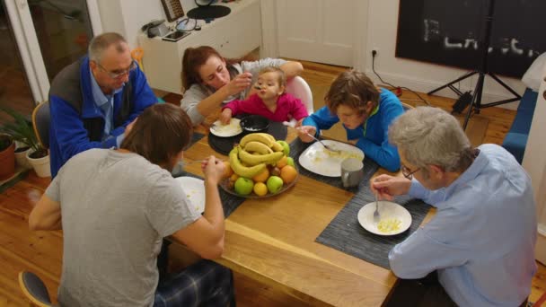 Hoge hoek uitzicht op grote multigenerationele familie zitten samen aan tafel, zetten eten op borden en gieten drankjes in glazen tijdens het hebben van vakantie diner thuis. — Stockvideo