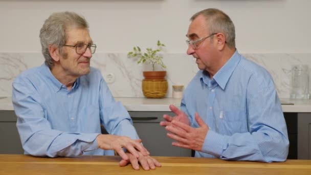 Two elderly men are talking at the table. Elderly communication concept — Stock Video