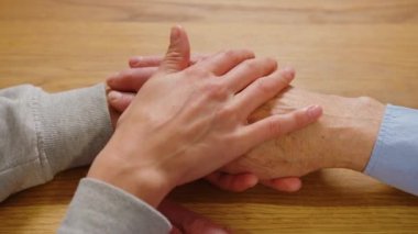 Rahatlatıcı bir el. Genç hemşire yaşlı adamı tutuyor.