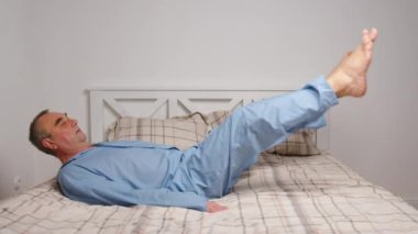 Yaşlı adam evde jimnastik egzersizleri yapıyor. Sağlıklı yaşam tarzı, fitness, eğlence, refah, emeklilik, yaşlılık kavramı.