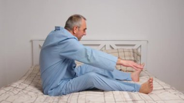 Yaşlı adam evde jimnastik egzersizleri yapıyor. Sağlıklı yaşam tarzı, fitness, eğlence, refah, emeklilik, yaşlılık kavramı.