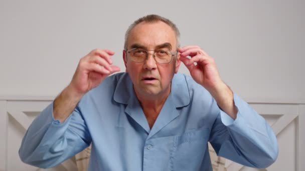 El anciano está sorprendido y sorprendido. Un hombre en sorpresa dispara gafas y mira a la cámara con sorpresa. — Vídeos de Stock