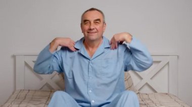 Mutlu, hayat dolu yaşlı adam rahat yatak egzersizleri yapıyor. Gülümseyen, emekli, esneyen, yatak odasında uzanan, enerji dolu, günaydın konseptinin keyfini çıkaran,.