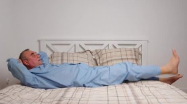 Yaşlı adam evde jimnastik egzersizleri yapıyor. Sağlıklı yaşam tarzı, fitness, eğlence, refah, emeklilik, yaşlılık kavramı.