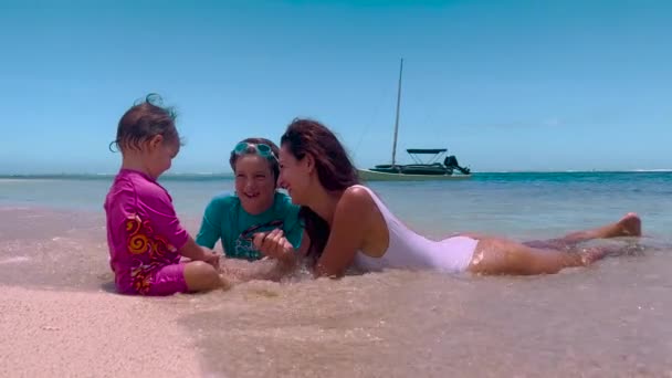 母親と子供たちはビーチに座っています。若いですcaucasian家族の母親女の子と男の子笑顔再生カジュアルな旅行ライフスタイルリラクゼーションパラダイスビーチ海愛する — ストック動画