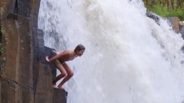 Genç maceraperest çocuk uçurumdan atlıyor. Muhteşem bir orman şelalesinden, tropikal bir tatil yaşam tarzından.