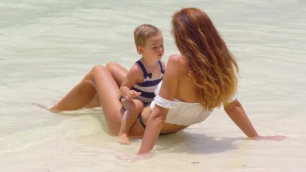 Jovem mãe e sua filhinha brincando e relaxando na praia do mar com areia nas férias de verão. Família feliz, conceito de paternidade — Vídeo de Stock
