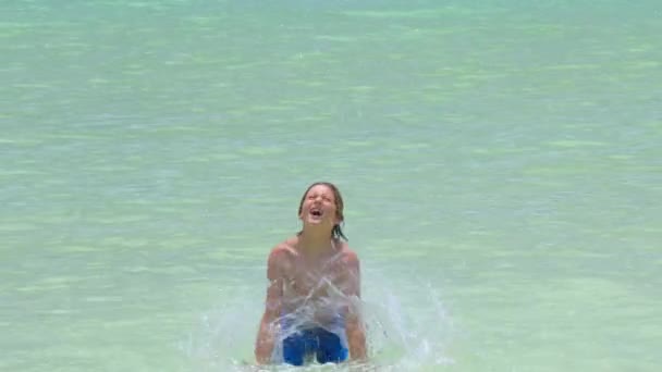 Мальчик плеснул водой в океан. Летние каникулы, отдых, семейная поездка в теплые страны — стоковое видео