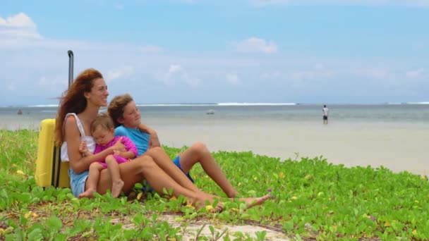Kobieta z rodziną i żółtą walizką na plaży — Wideo stockowe