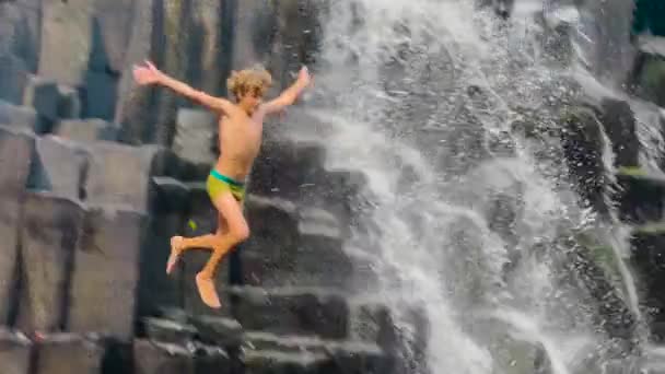 Zeitlupenaufnahmen eines Jungen, der in einen Wasserfall springt. — Stockvideo