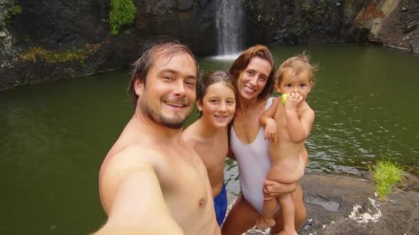 Батько щасливої сім'ї робить селфі з дружиною і дітьми на фоні водоспаду — стокове відео