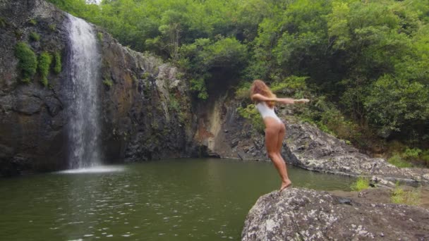 Serenity and Happiness. Beautiful young woman with arms outstretched enjoying waterfall. Sensuous female in white bikini. She is on vacation. — Vídeo de Stock