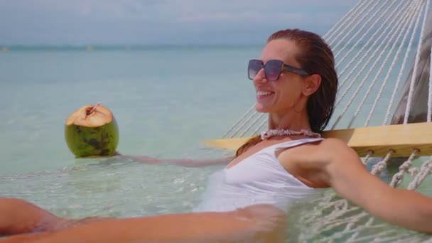 Woman relaxing in a hammock in the Caribbean. Girl drinking coconut. — стокове відео