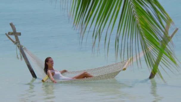 Una muchacha hermosa en un traje de baño blanco relaja mientras que miente en una hamaca y bebe un coco. Playa vacaciones concepto de lujo Océano Índico. Mauricio. — Vídeos de Stock