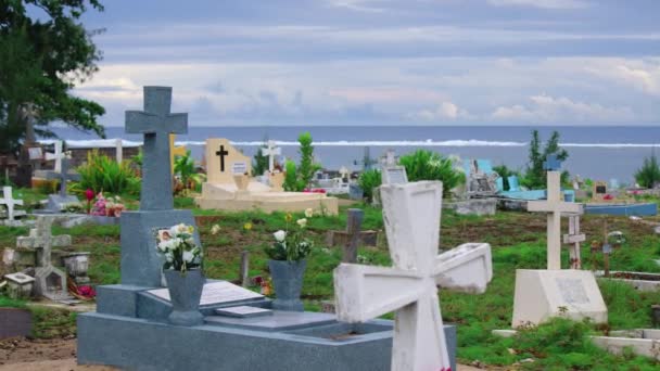 Crosses gravestones stand on the rocky shore as waves crash over the rocks. Oceanfront cemetery — Stockvideo