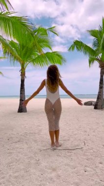 Vertical video. Mauritius, Indian ocean beach, woman relax near palms trees. Beauty girl at sea sand coast rest in summer sunny day. Epic tropical resort. Cinematic plot shot in 4K