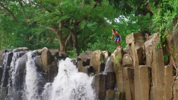 Slow motion beelden van een jongen springen in een waterval. — Stockvideo