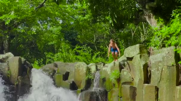 Imágenes en cámara lenta de un niño saltando a una cascada. — Vídeo de stock