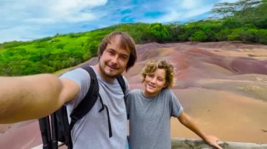 Güneşli bir yaz gününde gülümseyen baba ve oğul selfie çekiyorlar. Mauritius adasının muhteşem manzarasına maceralı bir yolculuk..