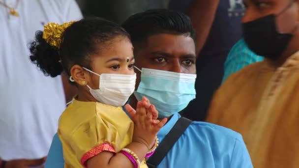 Mauritius, Ganga Talao, 18 januari 2022: Indisk familj i traditionell klänning med ett litet barn i famnen, vars ansikte är täckt med en ansiktsmask mitt i covid 19 — Stockvideo