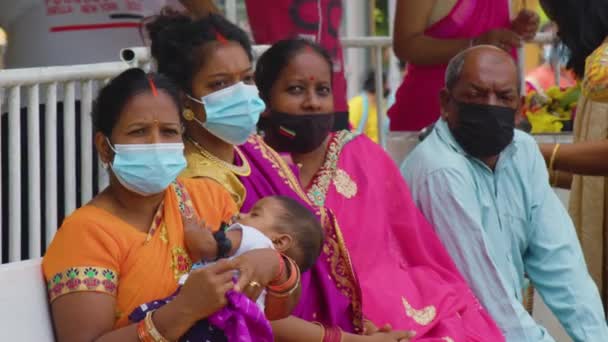 Mauritius, Ganga Talao, 18 januari 2022: Indiaas gezin in traditionele klederdracht met een klein kind in hun armen, wiens gezicht bedekt is met een gezichtsmasker te midden van de gemoederen 19 — Stockvideo