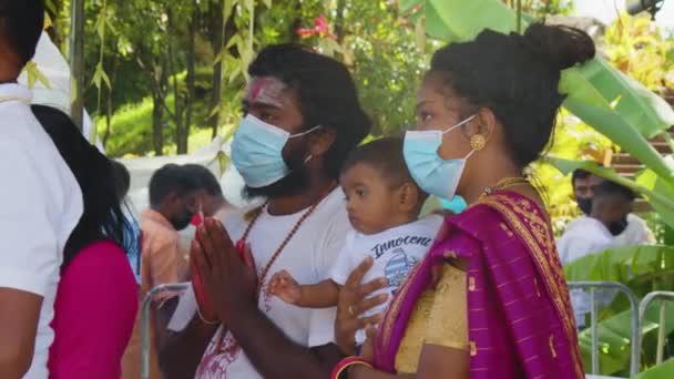 Mauritius, Ganga Talao, 18 januari 2022: Indisk familj i traditionell klänning med ett litet barn i famnen, vars ansikte är täckt med en ansiktsmask mitt i covid 19 — Stockvideo