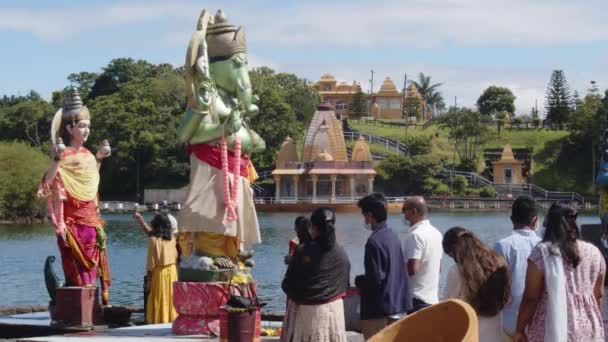Маврикий, Талао, 18 января 2022 года: индийские семьи в традиционной одежде пришли к священному озеру Талао, чтобы совершить ритуал и поклониться богам — стоковое видео