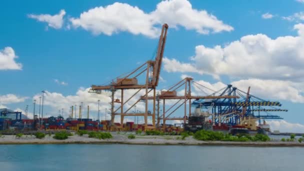 Desfasamento temporal. Vista da atividade em um porto de contêiner de carga movimentado com a chegada de um navio de carga comercial — Vídeo de Stock