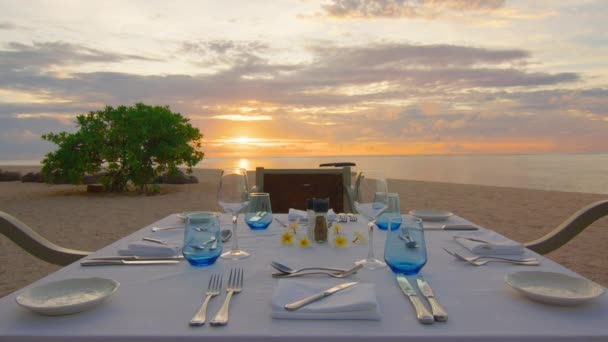 Point de vue depuis une plage de tables et chaises disposées à la plage pour un dîner romantique tout en regardant le coucher du soleil à destination de voyage populaire à Maurice — Video