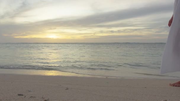Feminino de vestido branco pés andando descalço na costa do mar ao pôr do sol. Movimento lento. Fechar. — Vídeo de Stock