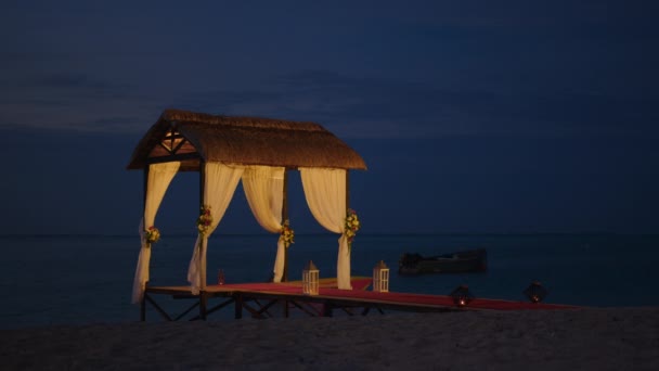 Bruiloftsstrand ingericht voor de kust. Bruidsboog aan de kust van de Indische Oceaan versierd met bloemen. Vakantie concept. Bruiloft gebeurtenis patronen eiland op zonsondergang — Stockvideo