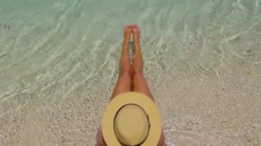 Plaj güneşi tatil konsepti. Beyaz kumlu cennet kumsalındaki kadın. Güneş banyosu yaparken bikini ve güneş şapkası takan bir kadın.