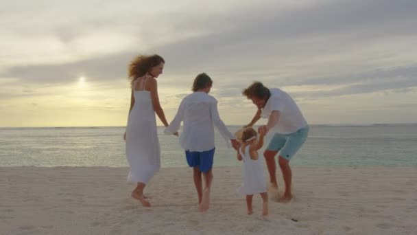 Siluetted fericit de familie joc și distracție pe plajă la apus de soare. Mişcare lentă. Conceptul de familie, libertate și călătorie. Familia se bucură și se distrează în aer liber stil de viață activitate. — Videoclip de stoc