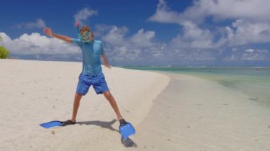 Sualtı maskeli, yüzgeçli mutlu bir çocuk Hint Okyanusu kıyısında dans edip zıplıyor. Mutluluk ve neşe kavramı