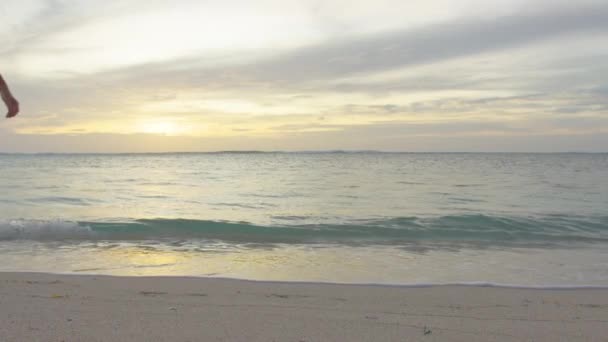 砂浜の海の波に沿って歩くスリムな女性の足と足。美しいです女性で白いドレス歩くと海辺のサーフ — ストック動画