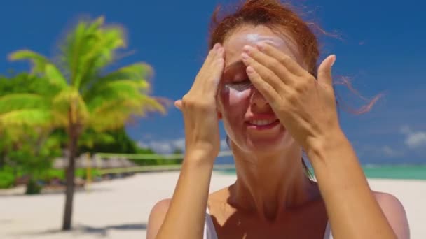 Жінка проходить сонцезахисний крем на обличчі в сонячний день — стокове відео