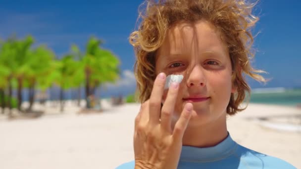 Madre che applica la crema solare sui neonati faccia sulla spiaggia al mare. Protezione solare e cura della pelle concetto — Video Stock