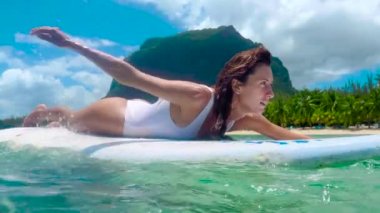 Kız sörf tahtasında yüzüyor. Güzel bir kız sörf yapıyor. Yavaş çekim