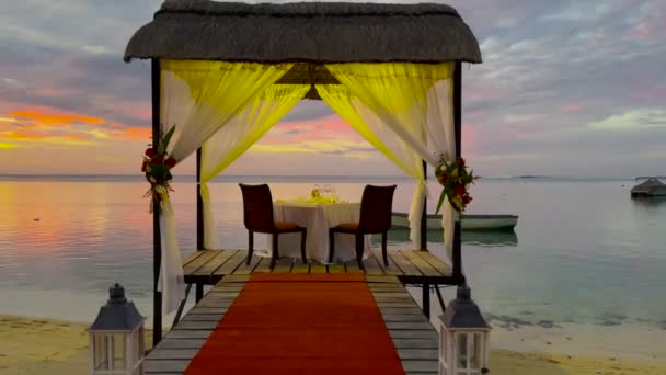 Romantische avondtafel voor twee personen op het strand bij zonsondergang op de achtergrond van prachtige wolken — Stockvideo
