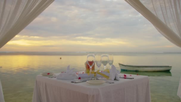 Romantic evening table for two persons on the beach at sunset on the background of beautiful clouds — Stock Video