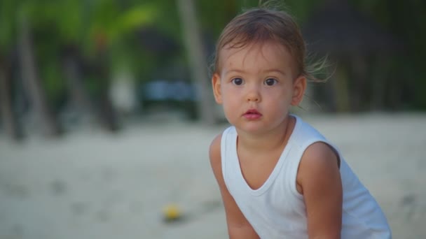 Nahaufnahme Porträt des schönen Babys. Haare wehen im Wind am Strand in Zeitlupe. Sie lächelt und ist attraktiv — Stockvideo
