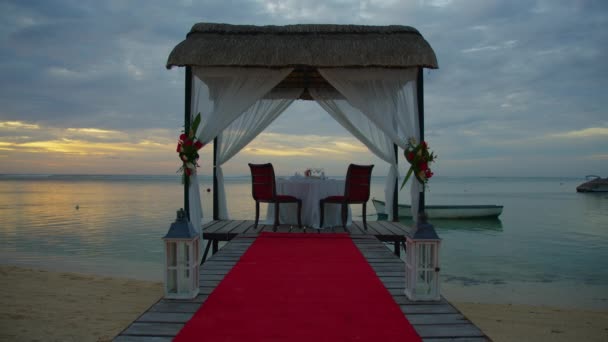 装饰一个节日餐桌。婚桌装饰。夕阳西下，在美丽的云彩衬托下，两个人在海滩上的浪漫餐桌 — 图库视频影像